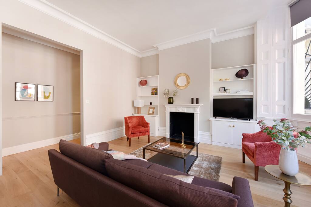 The living room with focus on the fireplace, sofa, chairs and the entrance from the hallway