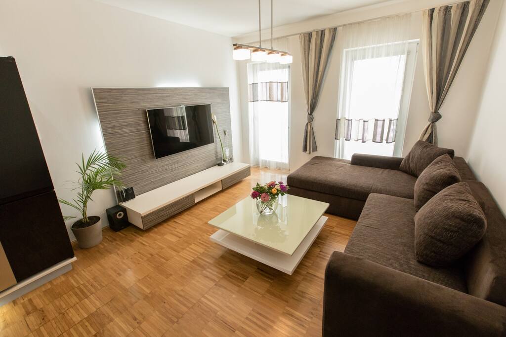 Living room area with flat screen, Apple TV, Wireless Speakers & International channel selection.