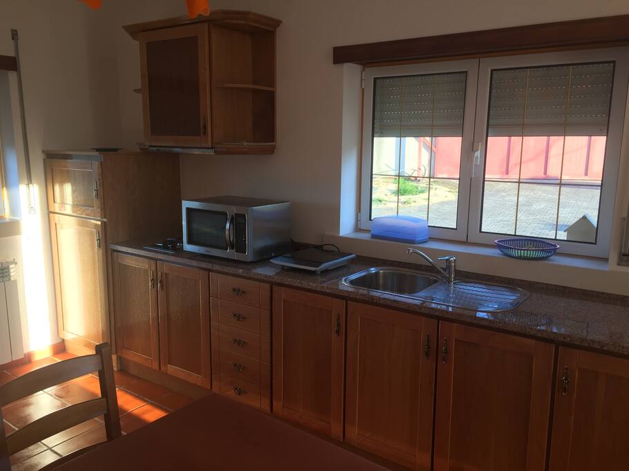 The kitchen space with a working fridge, a microwaves and an electric stove.