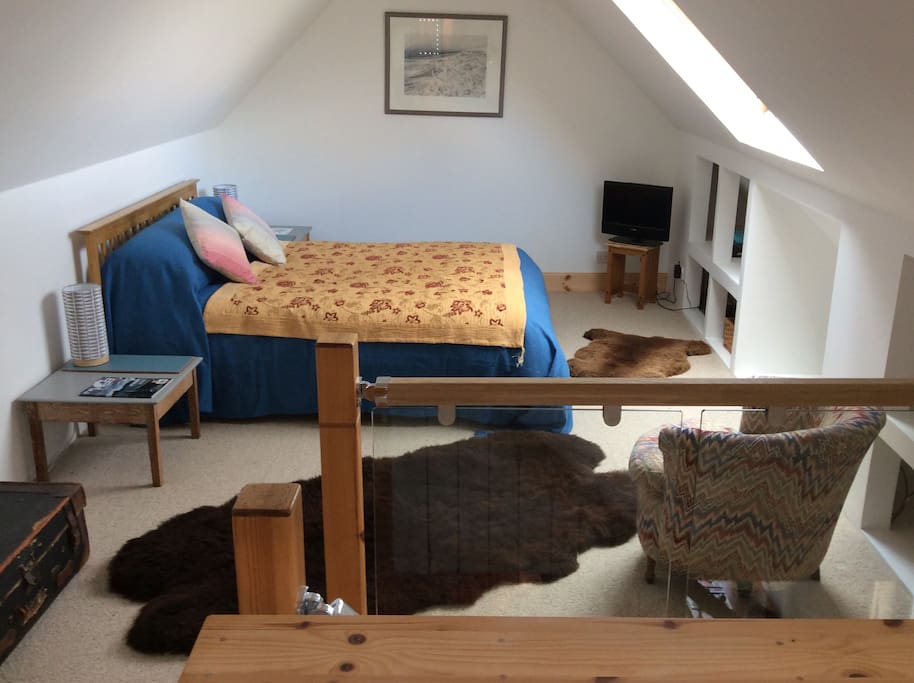 The bedroom with kingsize bed, scattered with sumptuous rugs from local sheep
