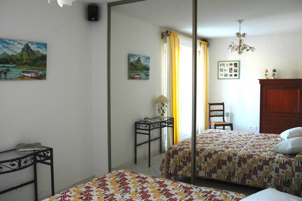 chambre lumineuse avec TV écran plat face au lit et accès terrasse