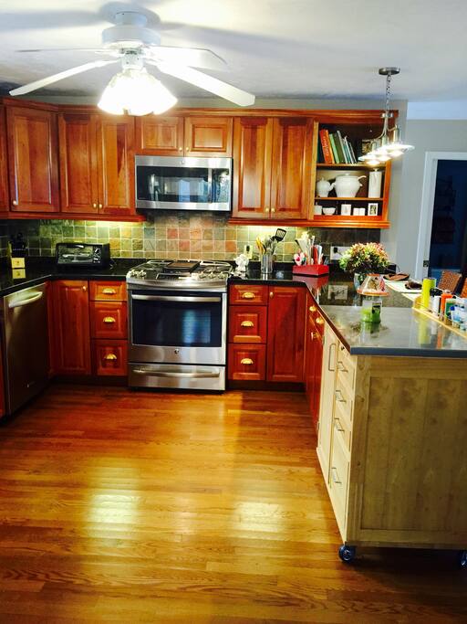 Kitchen view, GE stainless steel appliances, oak flooring, cherry cabinets, ceiling fan, granite countertops, rustic tile back splash and storage island.