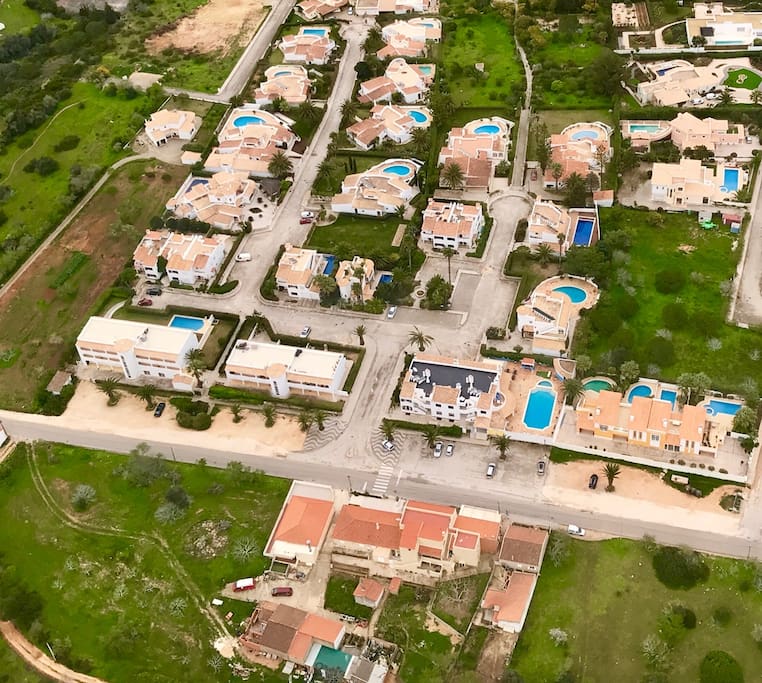 Apartment block has black roof to left of large pool