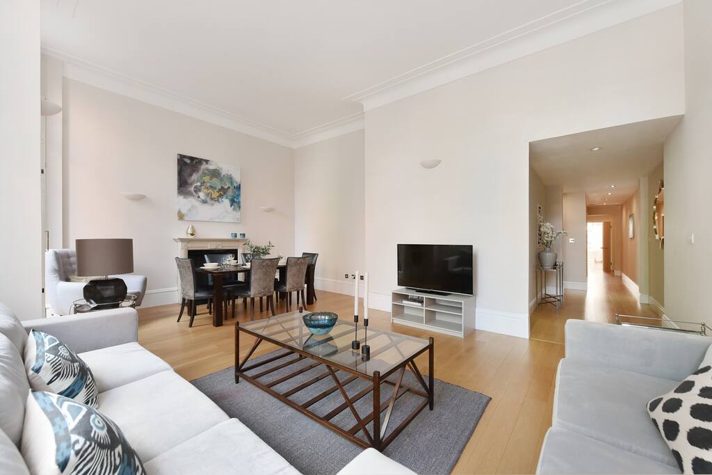The spacious, bright and elegant Lounge and dining area with TV and balcony overlooking the gardens