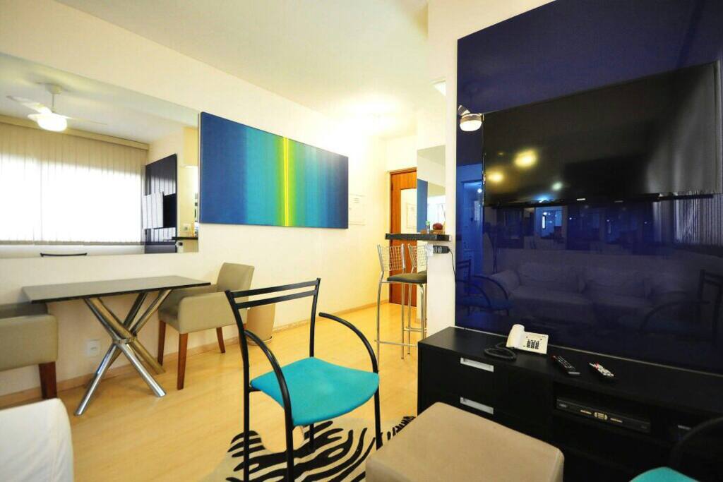 Espelhos na parede e tela azul e . Amarelo , onde tem
Mesa d granito negro , e 2 poltronas cor castor em couro , painel de vidro c tv , e rack