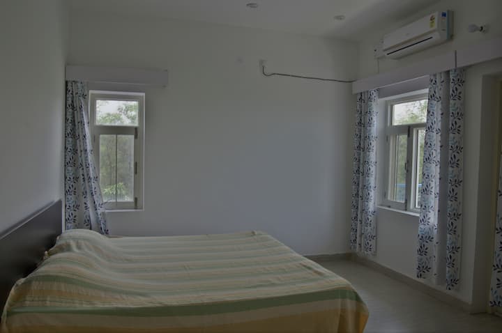 The well lit bedroom has windows on three side each with a good view of the adjacent forest (South), Pong reservoir (West) and Beas river and Dhauladhar range (North) respectively.