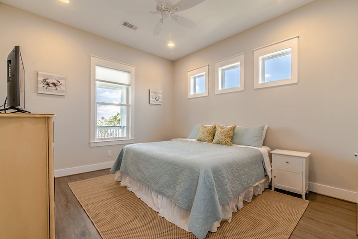 غرفة نوم في الطابق الثاني مع إطلالات على الخليج وسرير بمقاس كينج وتلفزيون ذكي.