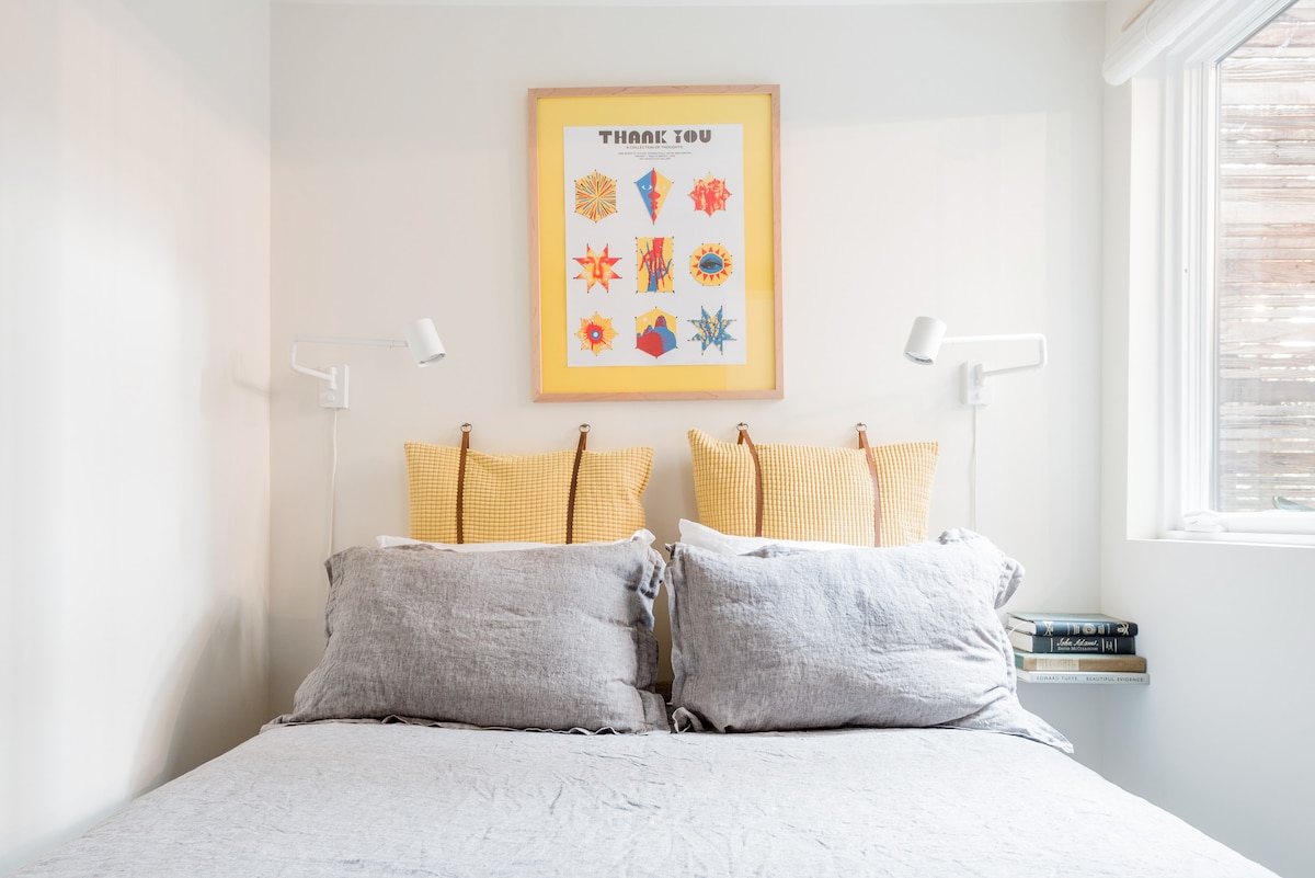 The bedroom features a queen bed, linen duvet, reading lights, and warming mattress cover