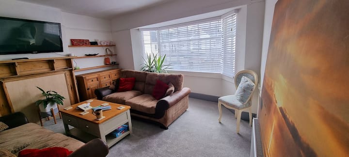 استرخِ مع نافذة كبيرة وأرائك كبيرة وكراسي إضافية وبيانو كهربائي وتلفزيون مع تطبيقات بث.