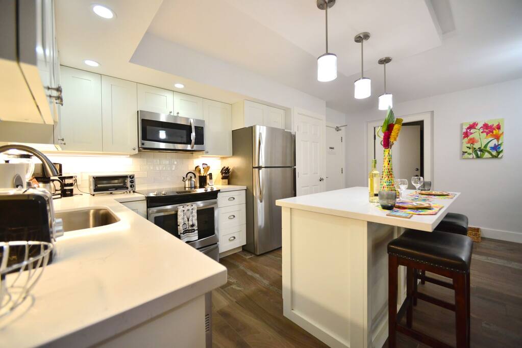 Remodeled kitchen features full-size stainless steel appliances (including a dishwasher, which is a rarity in most vacation homes), tile backsplash, and modern lighting.