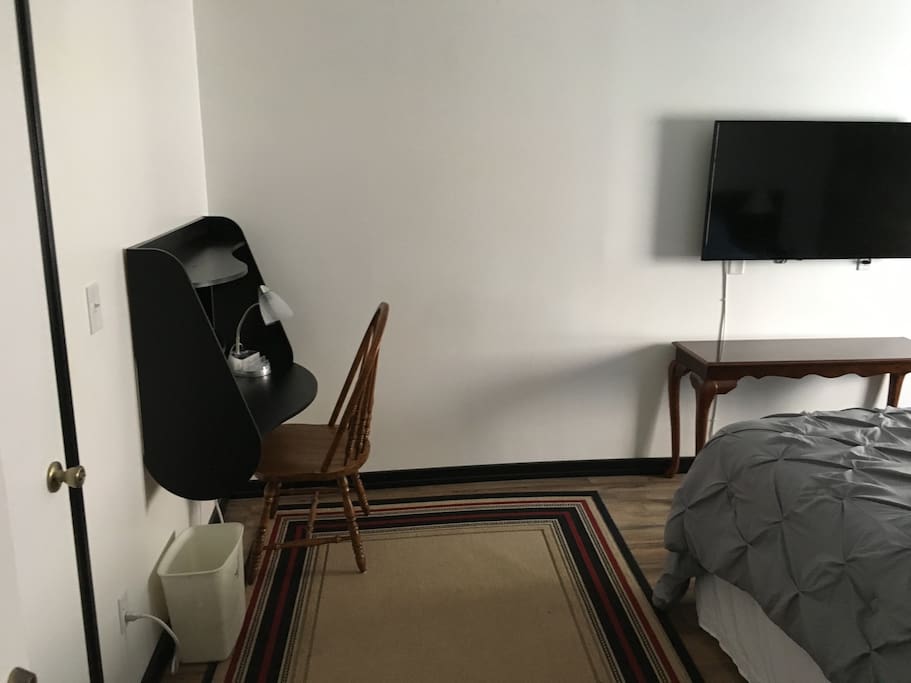 The main room includes a smart flat screen TV and a computer desk.