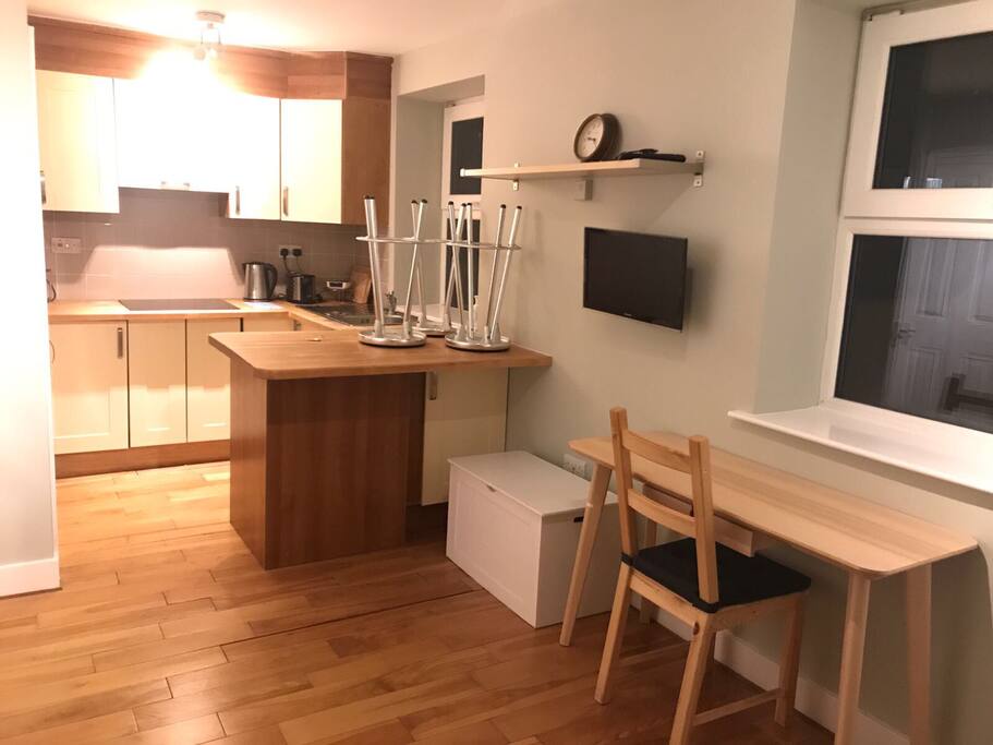 Clean modern living room and kitchen complete with modern appliances and sofa bed .