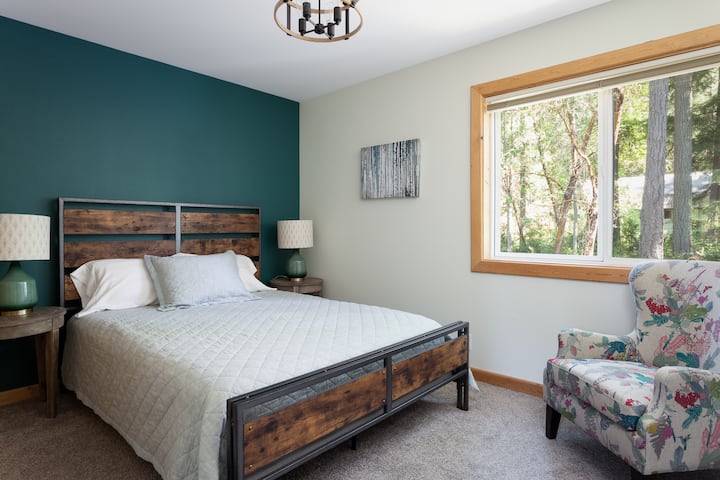 臥室4 （主樓層） ，配有1.8公尺寬雙人牀和裝飾牆。從大窗戶可以看到樹景。