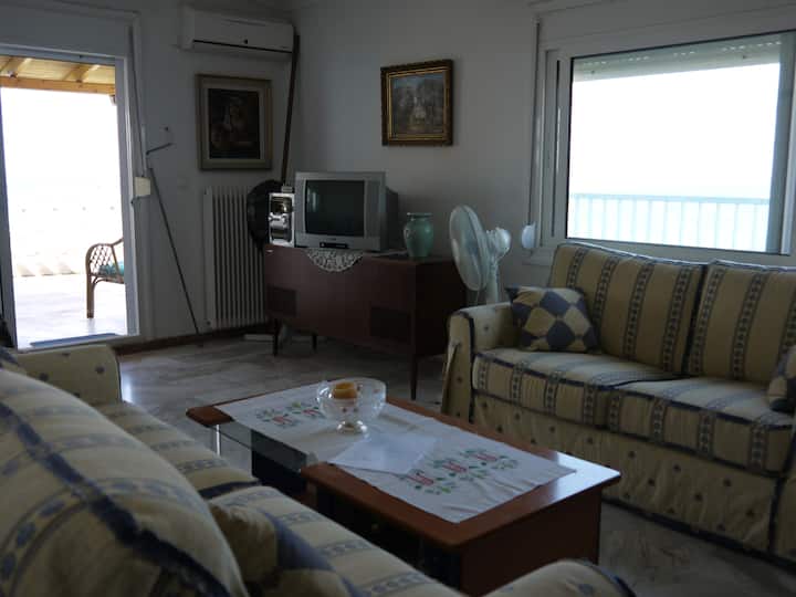 Dhoma e ndenjjes. Pamje nga deti nga dera dhe dritaret prej xhami.