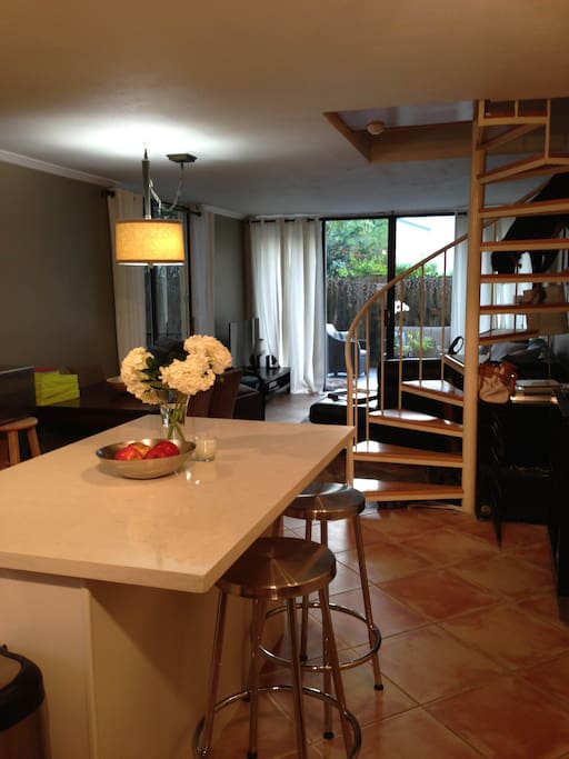 kitchen island. open space leading into dining and living room. stairs lead to bedrooms. patio doors lead to garden. bright and airy space!