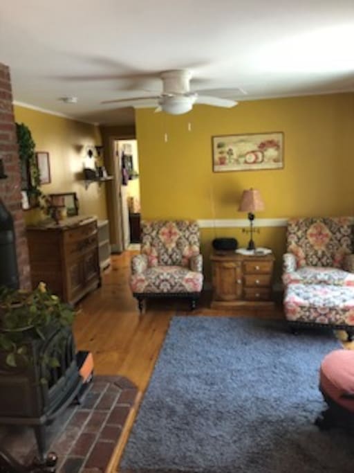 Sitting room with functional fireplace, view of the deck area, ceiling fan, seating for three