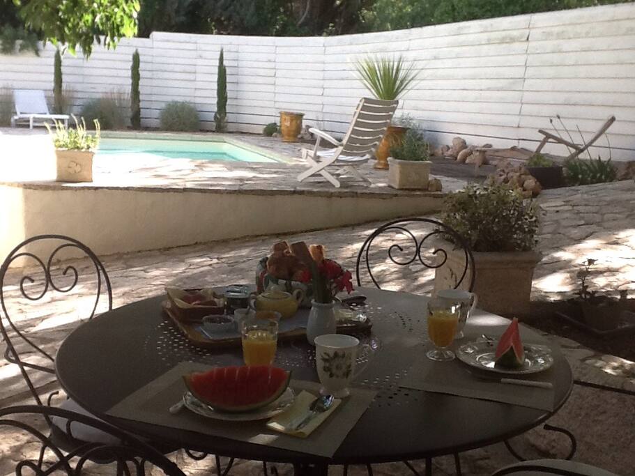 Petit-déjeuner servi en terrasse ombragée au bord de la piscine...