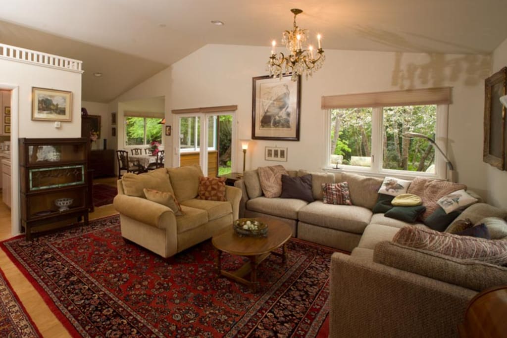 Living room with family heirlooms and carpets is open to the dining nook and the outdoors.