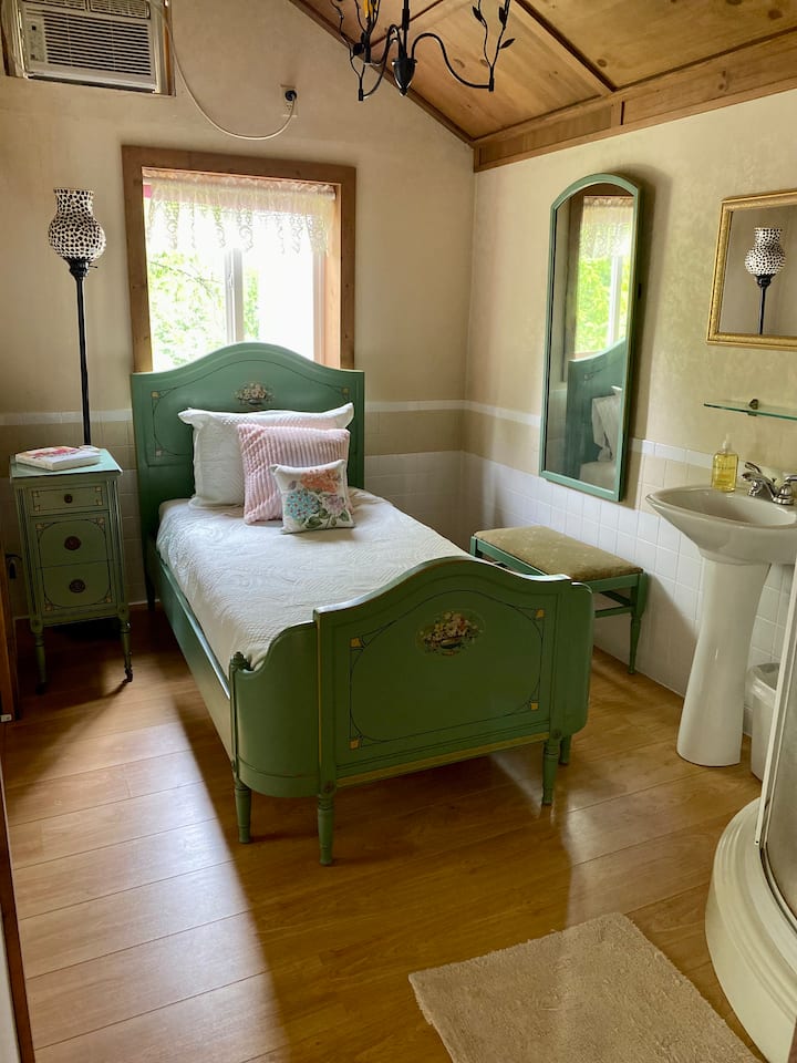 Detailed view of downstairs bedroom on the right with twin bed and shower.