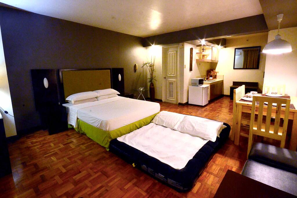 Queen bed (for 1-2 pax), optional airbed (for 3-4 pax). The white door between the bamboo plant fixture and refrigerator/microwave opens to the toilet. The main door (hidden from view) is next to the mirror on the right hand side of the photo.