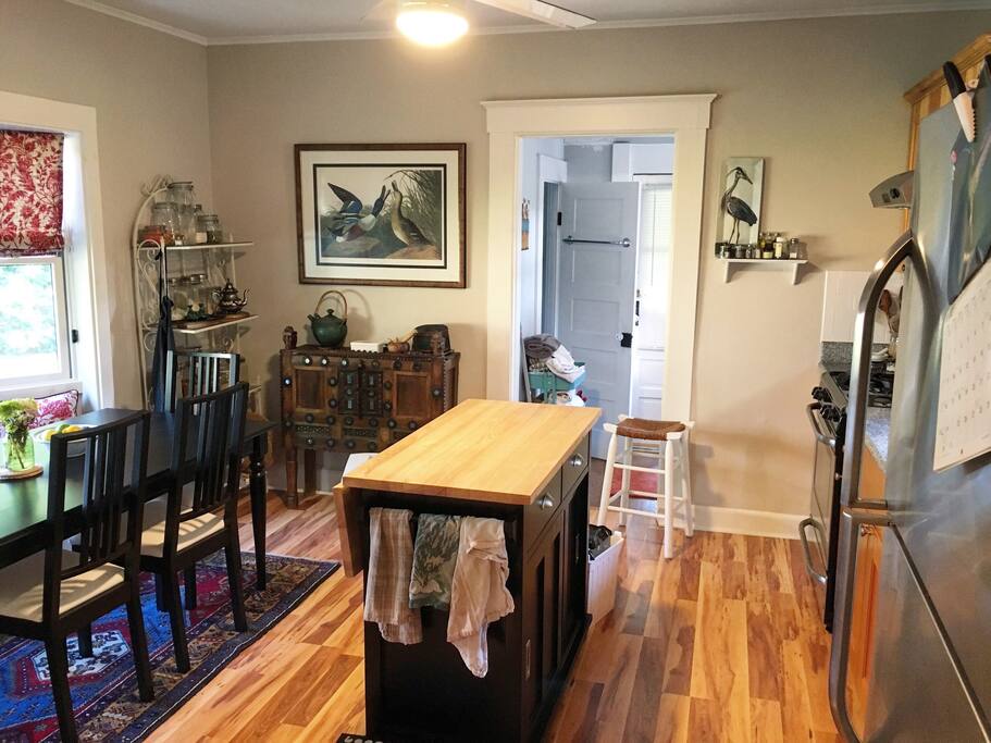 Kitchen with moving island, large fridge and freezer, dishwasher, dining area/workspace, gas stove, oven, pantry closet.