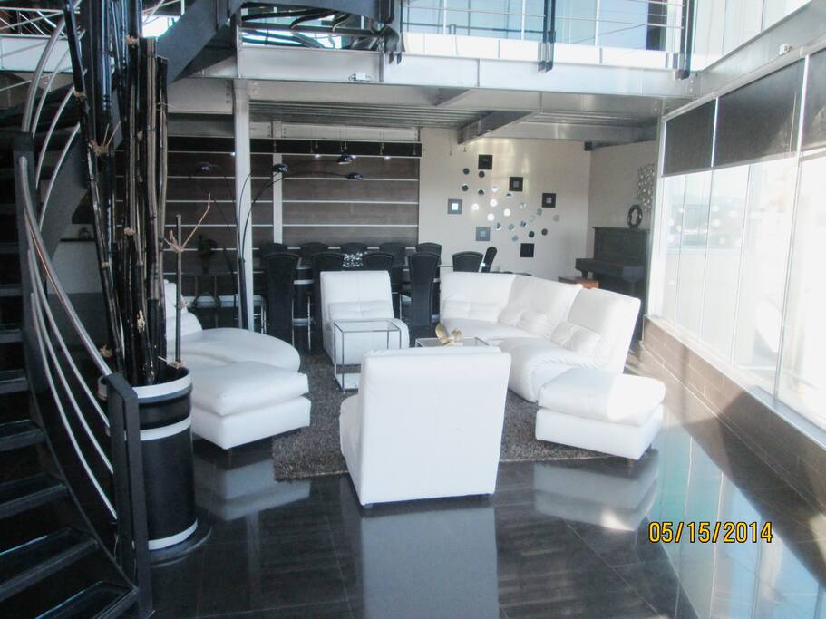 azulejos negros, colores plata en las vigas tipo industrial, escalera con escalones de vidrio y espacios amplios.