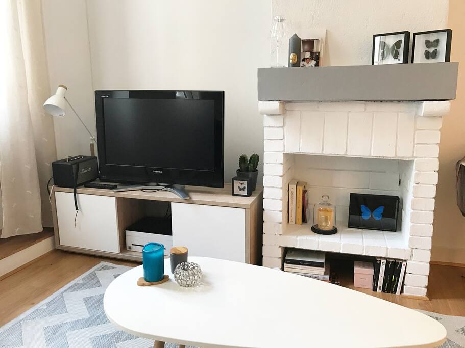 Salon avec cheminée décorative et TV