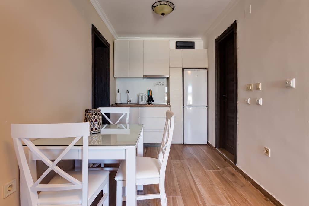 Kitchen equipped with fridge, teapot and dishes.