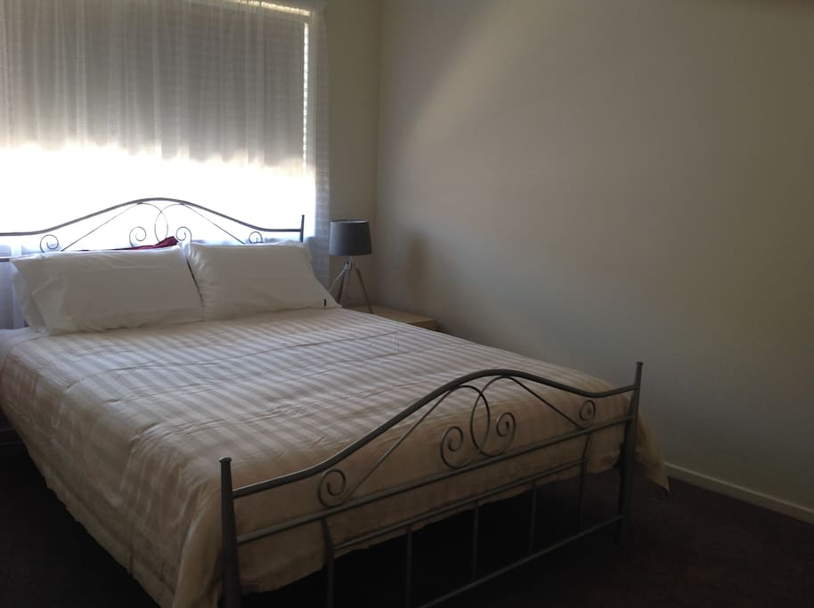 Queen size bed, with fan in room.