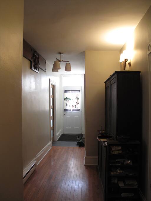Room is at the front of the house. Long hardwood halway with antiques