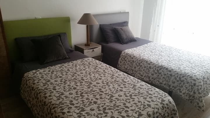 Segundo dormitorio con dos camas individuales y acceso a un pequeño balcón.