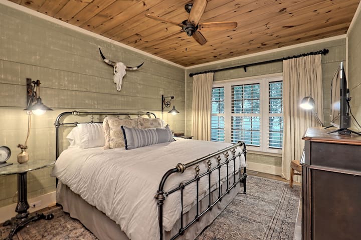 ห้องนอนชั้นบนพร้อมเตียงคิงไซส์ทีวีจอแบนขนาดใหญ่และวิวภูเขา เฟอร์นิเจอร์โทนสีคู่, pully sconces, โครงเตียงเหล็กและกะโหลกบังคับลองฮอร์นแท้ๆทำให้ห้องนี้ให้ความรู้สึกแบบชนบทที่ไม่เหมือนใคร 