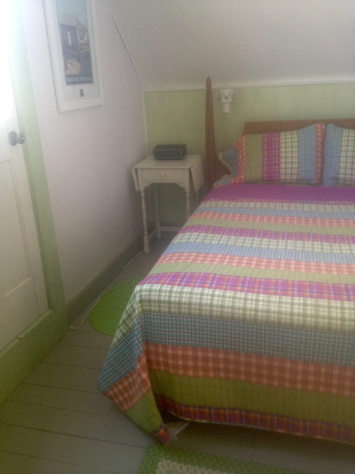 Front bedroom. Queen bed is up against the wall. Door opens to working balcony.