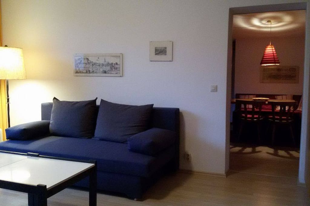Wohnzimmer mit Schlafcouch links im Bild und Gemütliche Sitzecke mit Esstisch im weiteren Zimmer - rechts im Bild