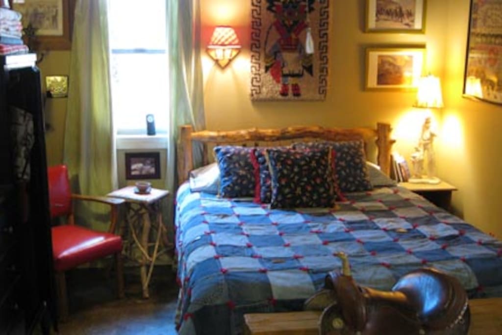 Cowboy Dreamland: Log bed, custom denim comforter, Mexican saddle, red leather chair and western art