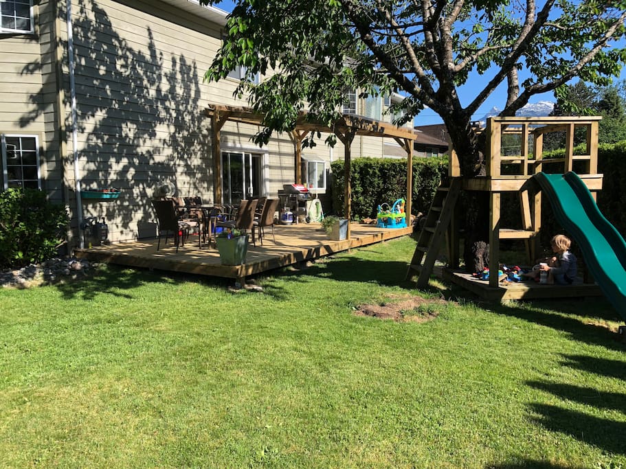 Sunny yard with fruit trees, tree house and slide