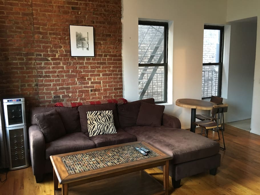 Main room with exposed brick, high ceilings and cedar beam accents. The perfect place to relax and enjoy some down-time after an exciting day in the city. Working wine fridge. Surrounded by windows and light. Couch can comfortably sleep 1+