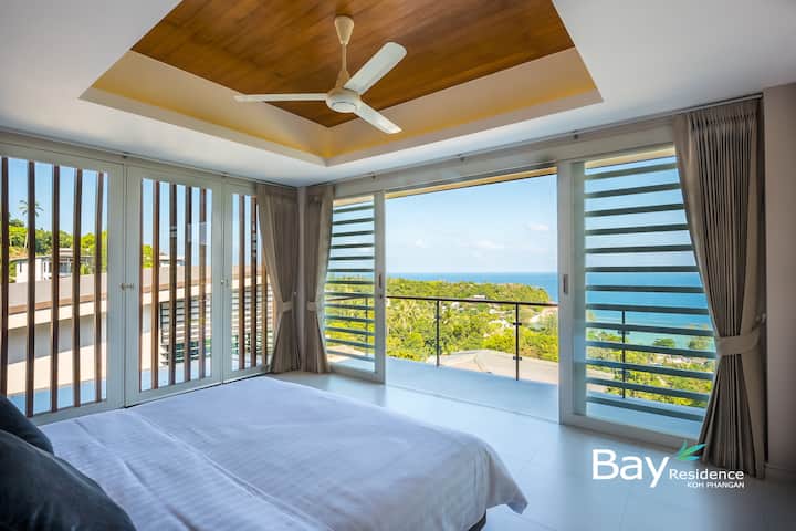 ตื่นมาชมวิวทะเลที่สวยงามในห้องนอนที่เงียบสงบนี้ มีหน้าต่างสูงจากพื้นจรดเพดาน เพดานไม้ และพัดลมระบายความร้อนที่สะดวกสบาย
