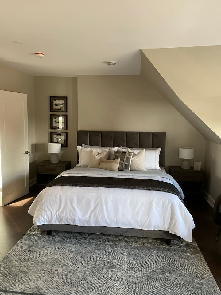 Ძირითადი საძინებელი დიდი ზომის საწოლით, დიდი ბრტყელეკრანიანი ტელევიზორითა და დასაჯდომი ადგილით.