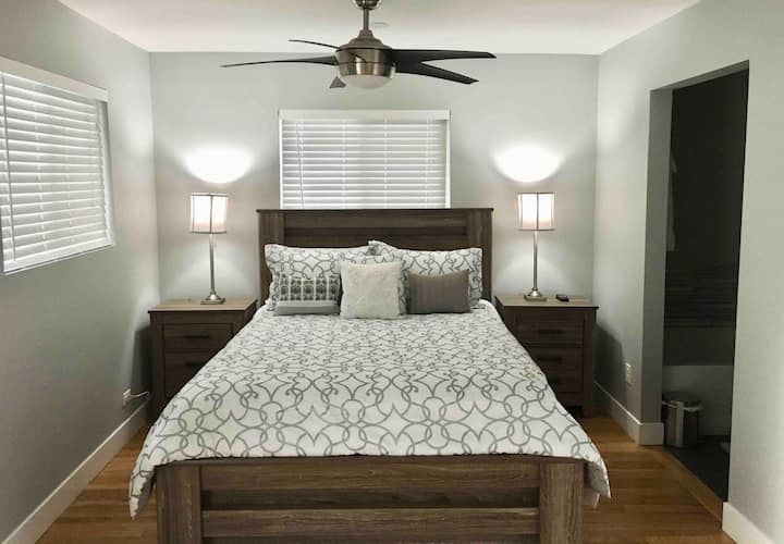 Dormitorio principal con cama de dos plazas, baño privado, vestidor y puerta corrediza que conduce al patio al aire libre. 