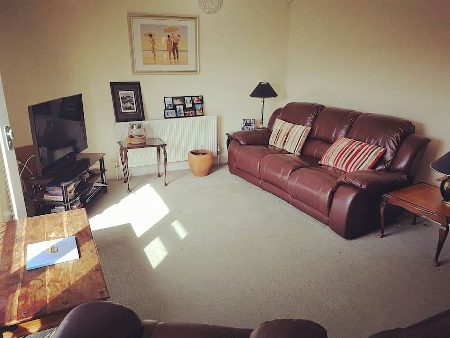Lounge with one large reclining sofa, one medium reclining sofa and one armchair that also reclines. Large flatscreen TV with Amazon firestick. Double doors that open from the first floor onto a Juliet balcony giving lots of light from the garden.
