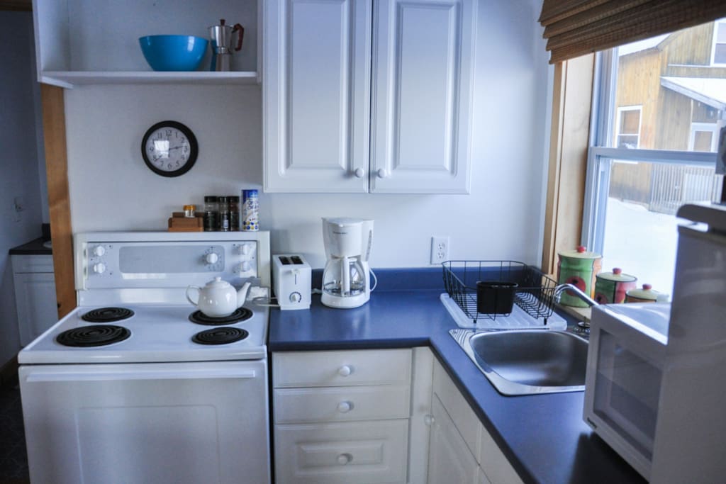 The kitchen is fully equipped for cooking with pots, plates and cutlery.