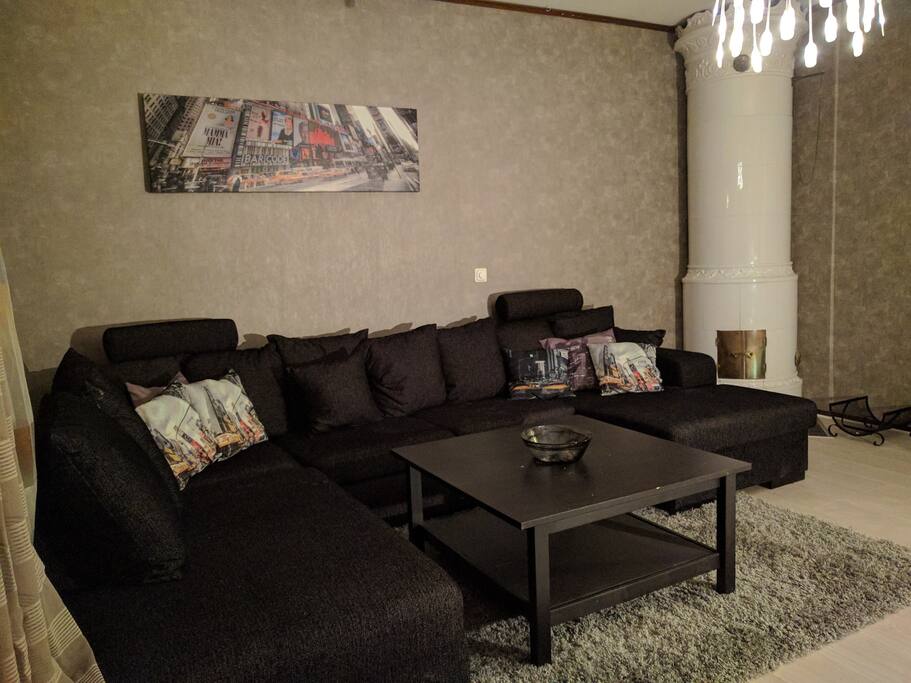 Vardagsrum med stor och bekväm soffa och mysig kakelugn, godkänd att elda i.