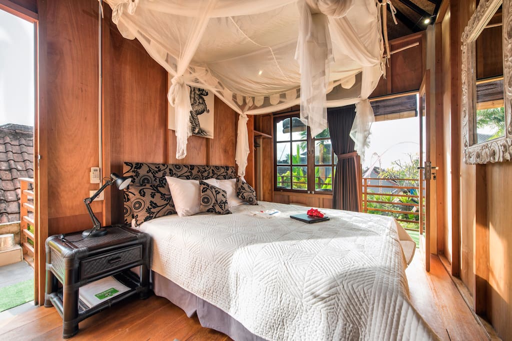 Lumbung suite with wooden floors and walls, enclosed ensuite bathroom and romantic draped net. Has air-con and fan cooling, Queen bed, quality cotton linens and views from the veranda.
