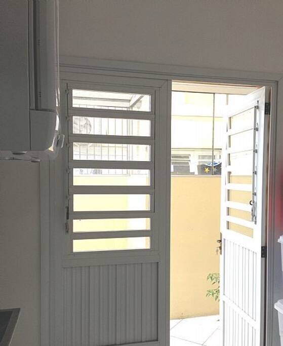 Área de serviço com lavadora de roupas, secadora, área externa coberta.
