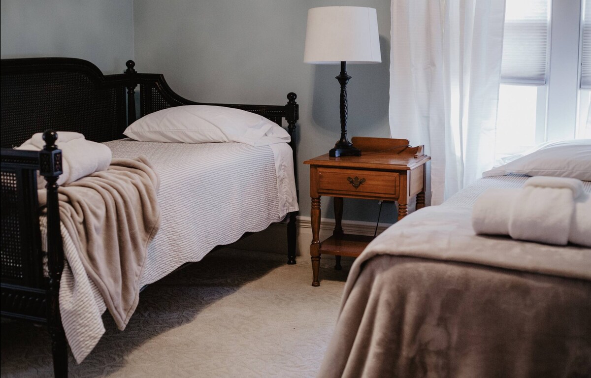 3号卧室：两张单人床和带窗式空调的衣柜空间。