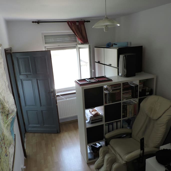 Bedroom: personal library, massage chair, window with blinds.