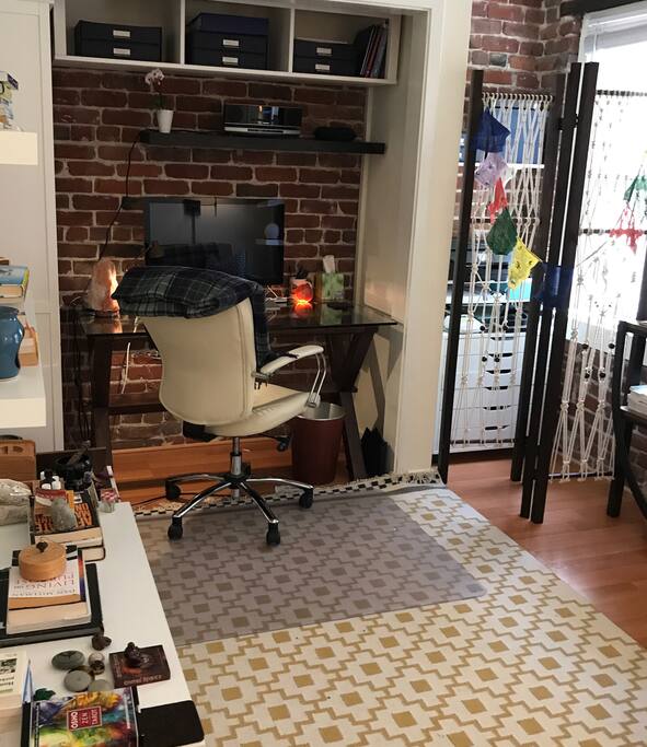 Work desk within the enclave of the home office. A 27 inch Mac Display with Bluetooth keyboard and trackpad conveniently connects to your MacBook laptop for a larger more functional viewing experience. A white leather office chair allows for comfortable seating and finishes the look.
