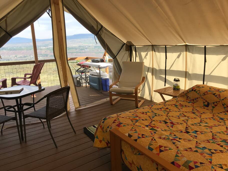 Looking from the back corner of the tent out toward the front. There's a table with two chairs and a comfy chair for relaxing indoors.