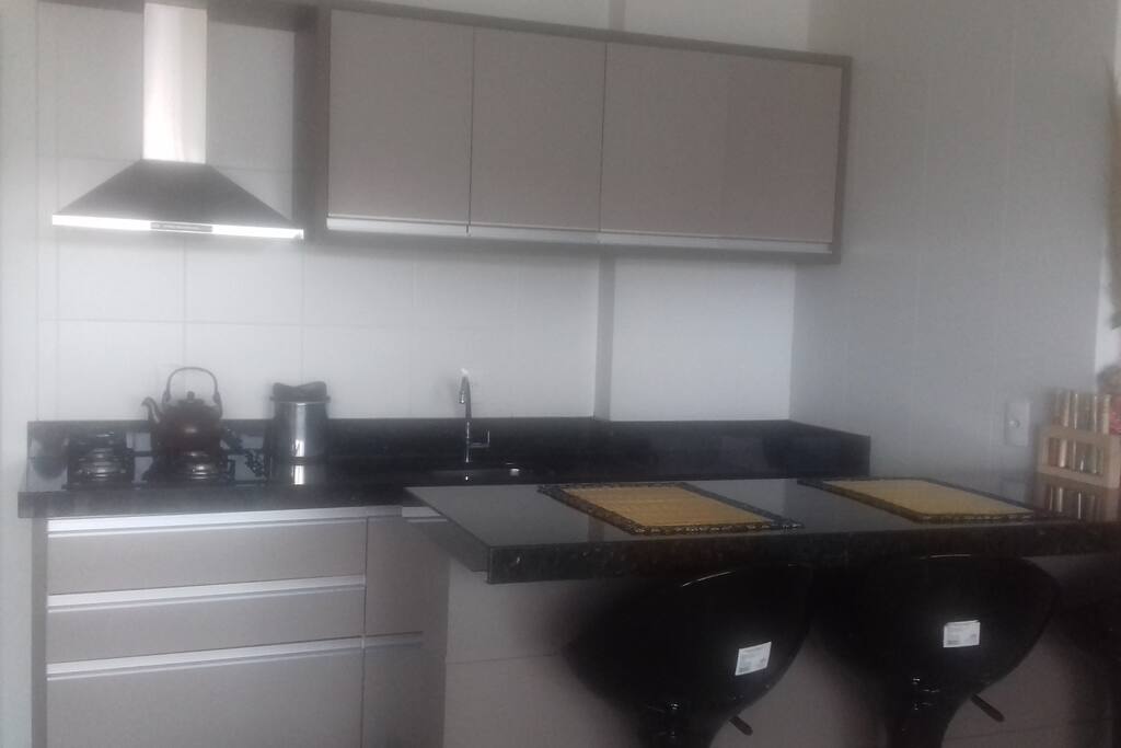 Cozinha com bancada; à esquerda a lavanderia